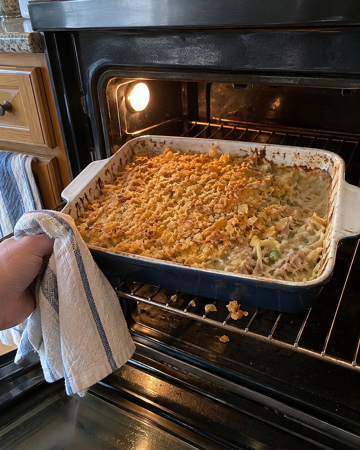 A tuna noodle casserole with a patchy crushed-chip topping on an oven rack.