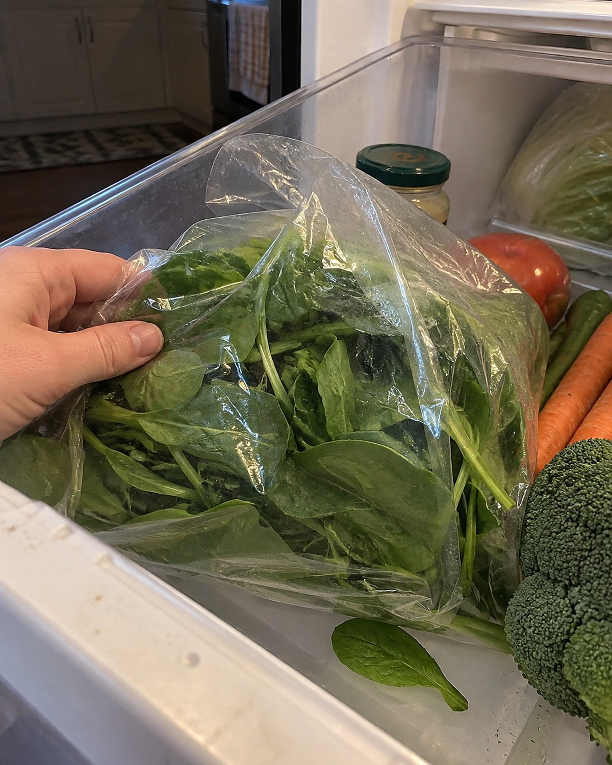 Damp bagged greens slump against the side of an open vegetable drawer.