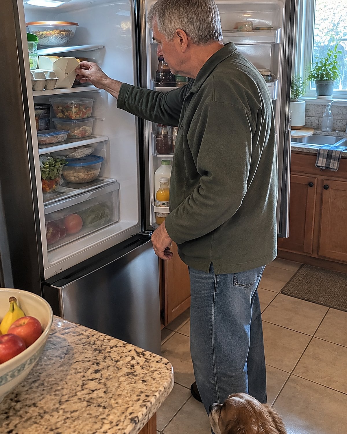 A hand pulls a worn takeout carton from behind an egg carton in the fridge.
