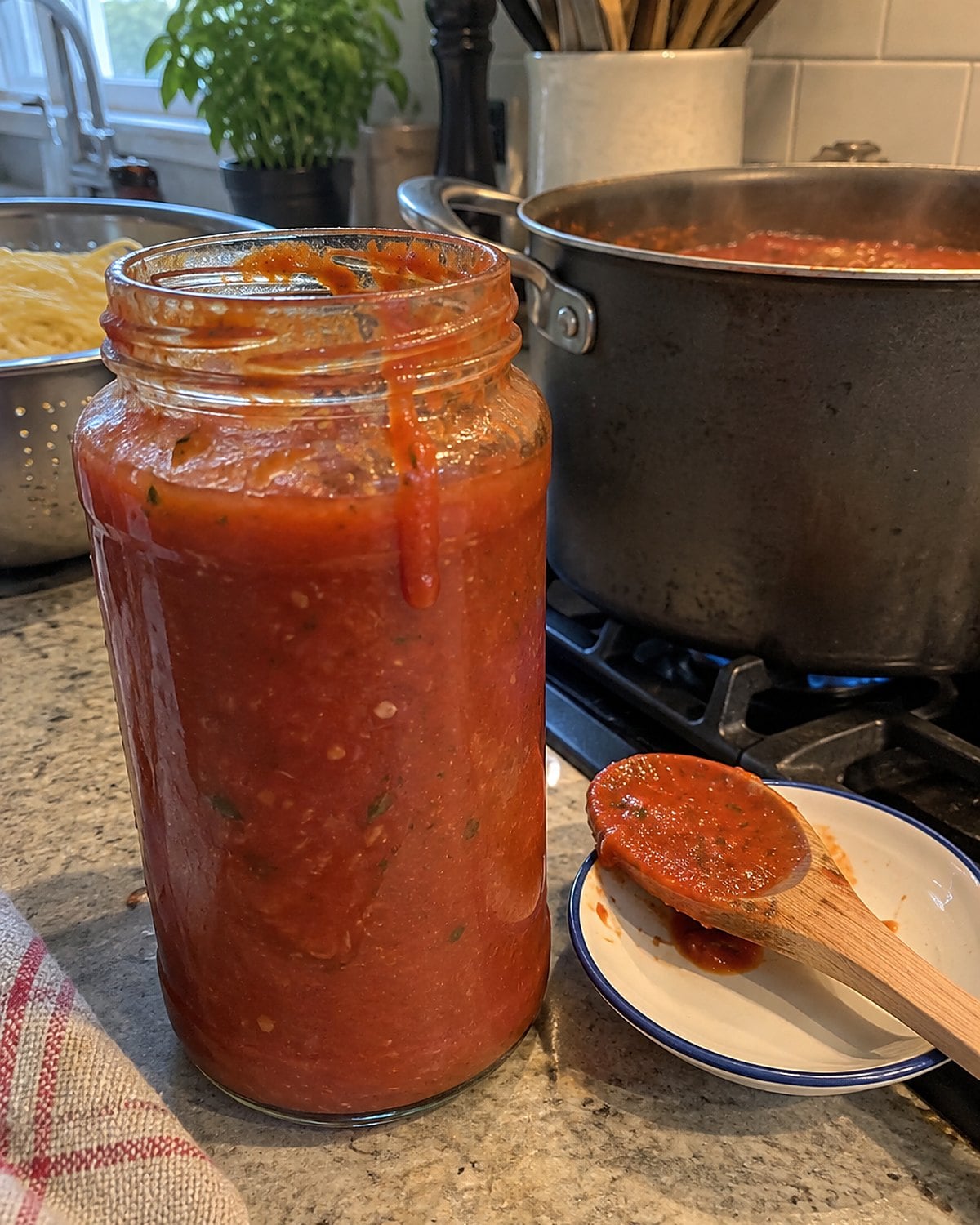 An opened pasta sauce jar with a stained rim stands beside a pot on the stove.