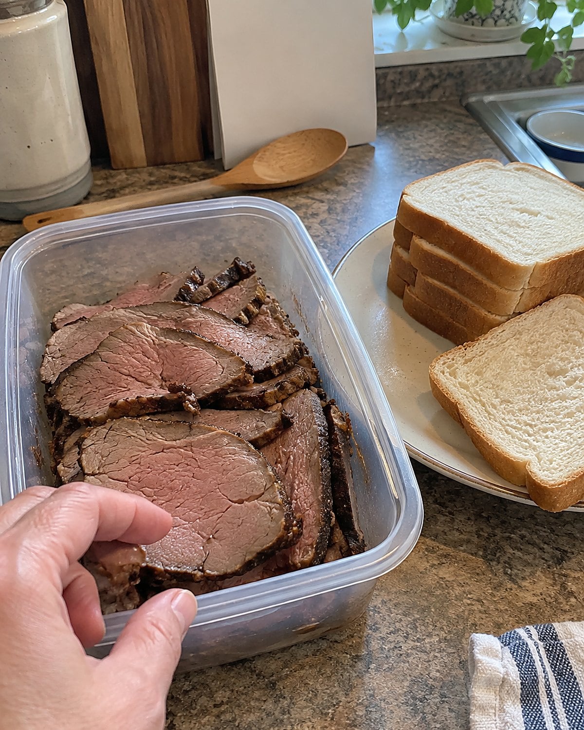 A container of sliced roast sits by a kitchen calendar and a stack of sandwich bread.