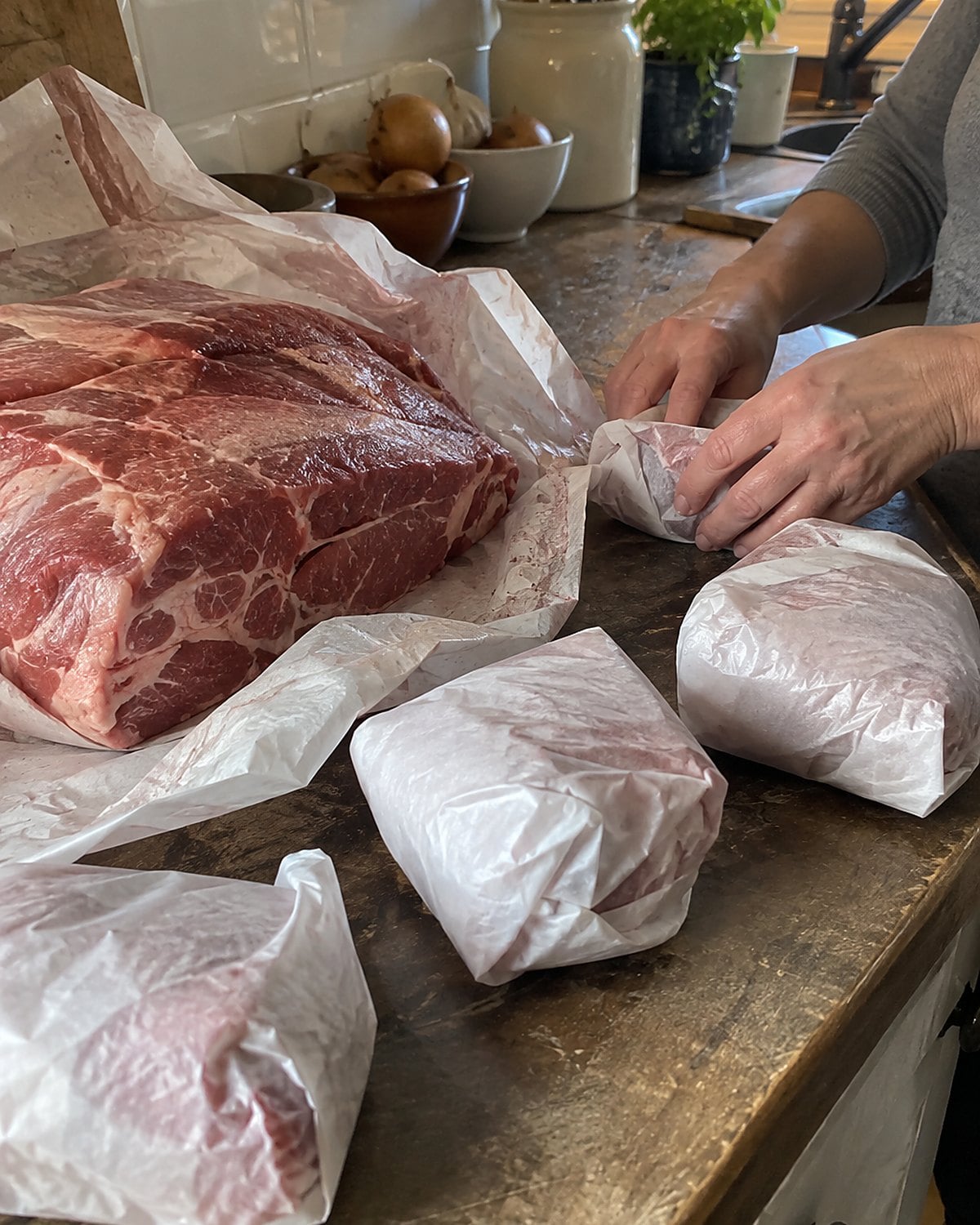 A family pack of meat lies beside smaller wrapped portions on a market-stall counter.
