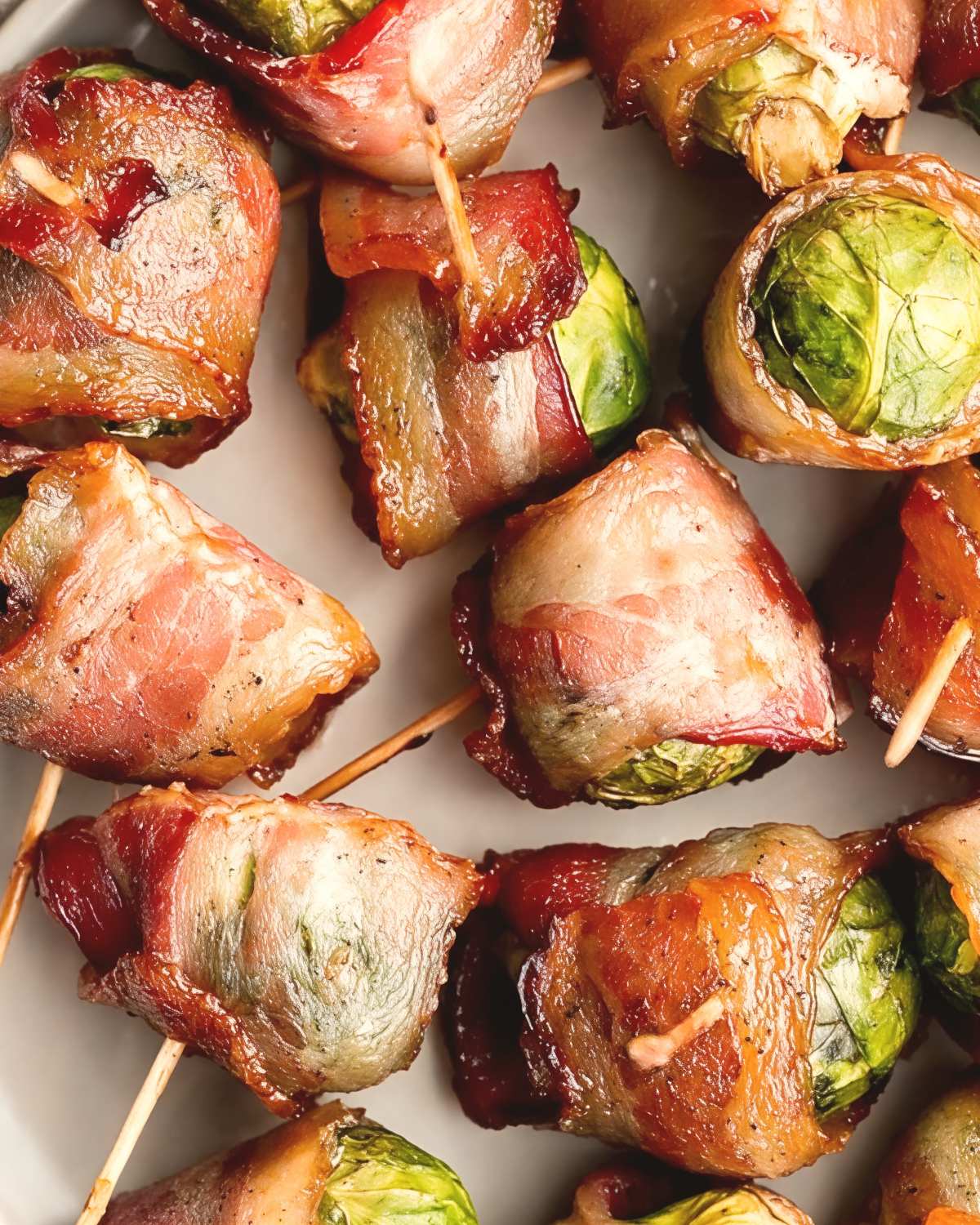Crispy bacon-wrapped brussels sprouts secured with toothpicks on a plate, perfect for savory gluten free thanksgiving appetizers.