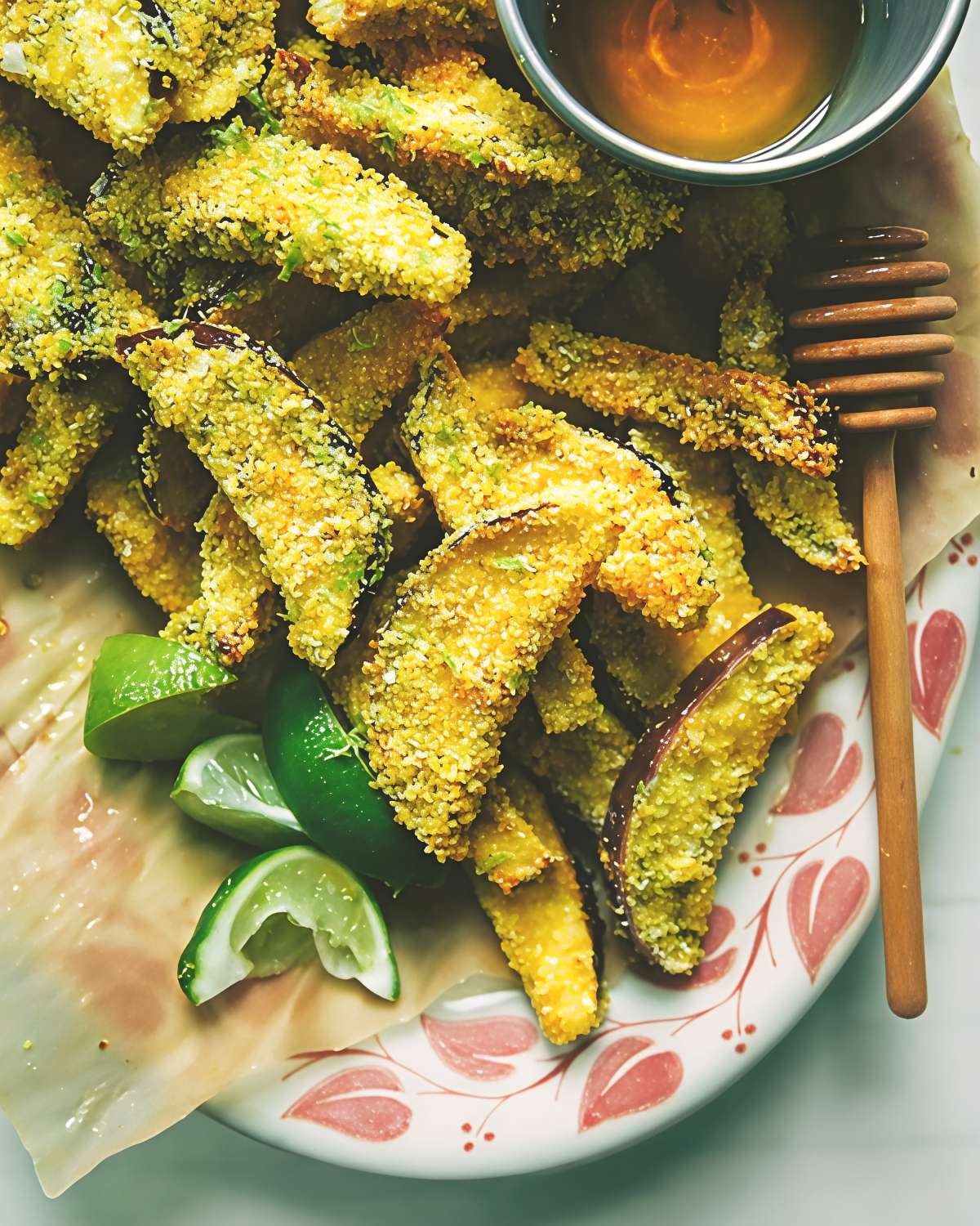 Golden crispy eggplant polenta bites served on a platter with fresh lime wedges and a side of honey, ideal for delicious gluten free thanksgiving appetizers.