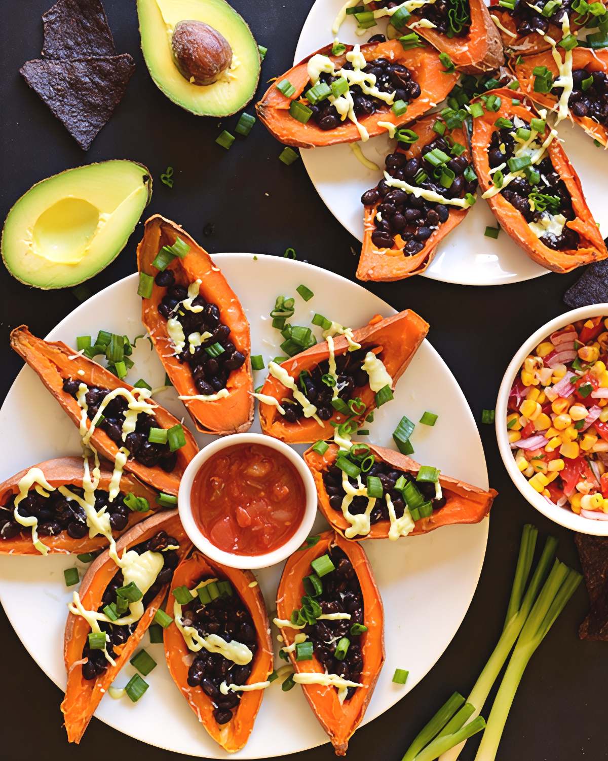 Roasted sweet potato skins stuffed with seasoned black beans, green onions, and avocado crema arranged around a bowl of salsa, ideal for vibrant gluten free thanksgiving appetizers.