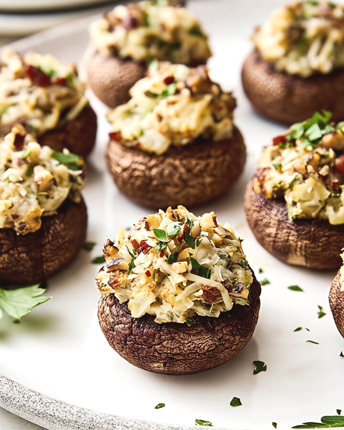 Savory baked stuffed mushrooms filled with herbs and cheese on a white platter, perfect for easy gluten free thanksgiving appetizers.