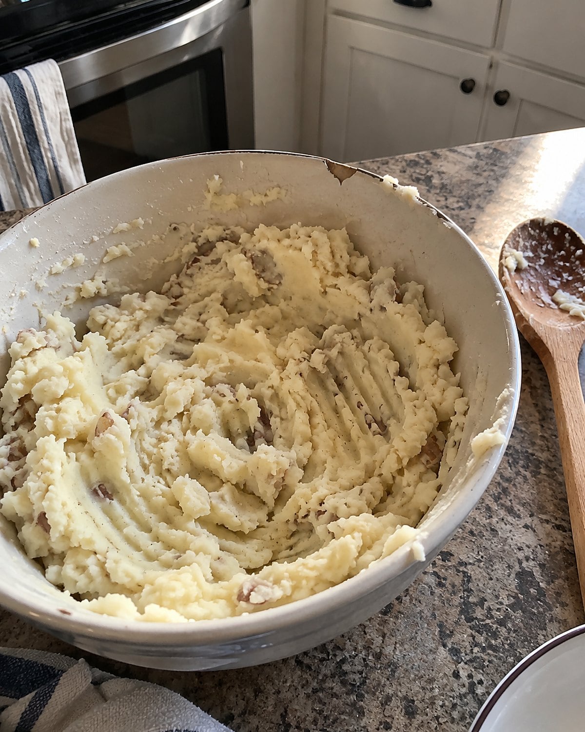 Fork marks through mashed potatoes in a chipped bowl on the counter.
