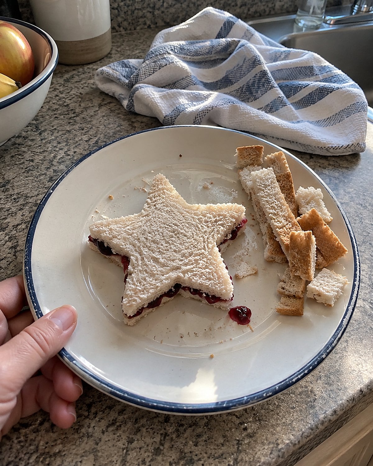 A star-shaped jelly sandwich on a plate with bread scraps beside it.