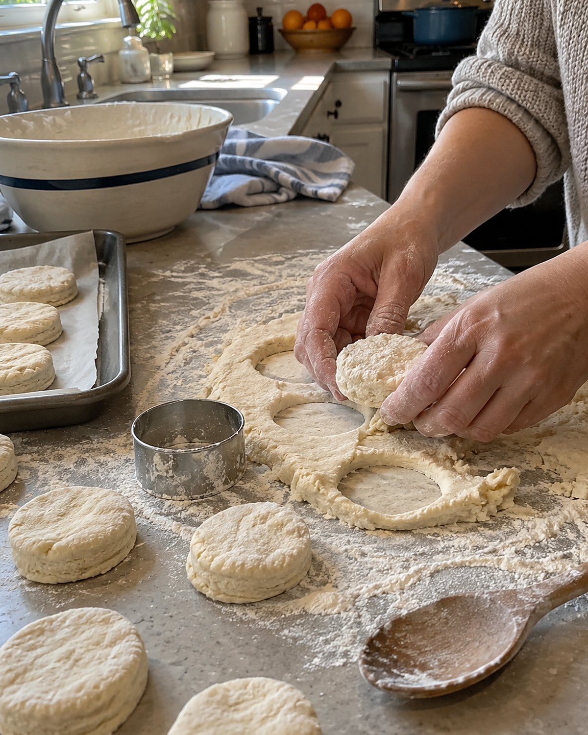 A floured biscuit cutter stands beside uneven rounds of dough on a counter.