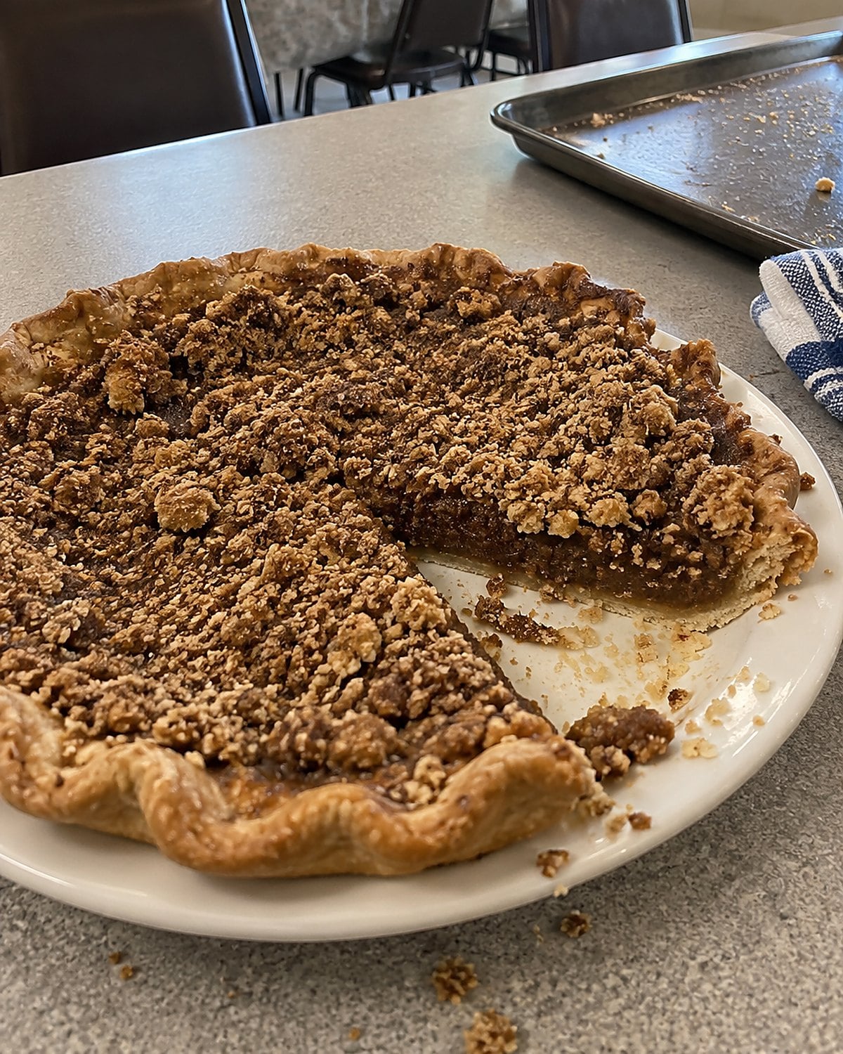 A shoofly pie with rough crumbs on top sitting on a church hall table.