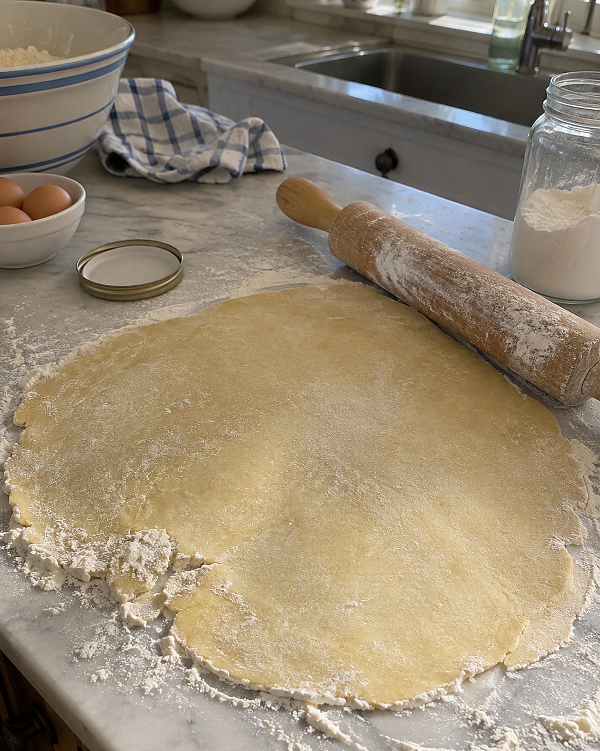 A floury rolling pin resting beside a rough circle of dough on the counter.