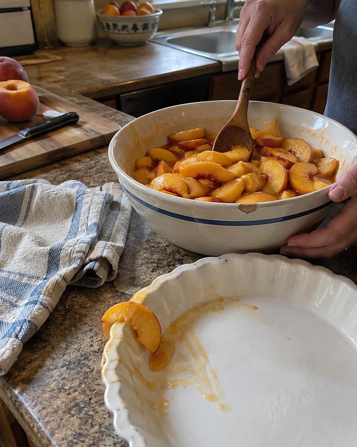 Sliced peaches and their juice in a bowl beside a pie plate on a market-worn counter.
