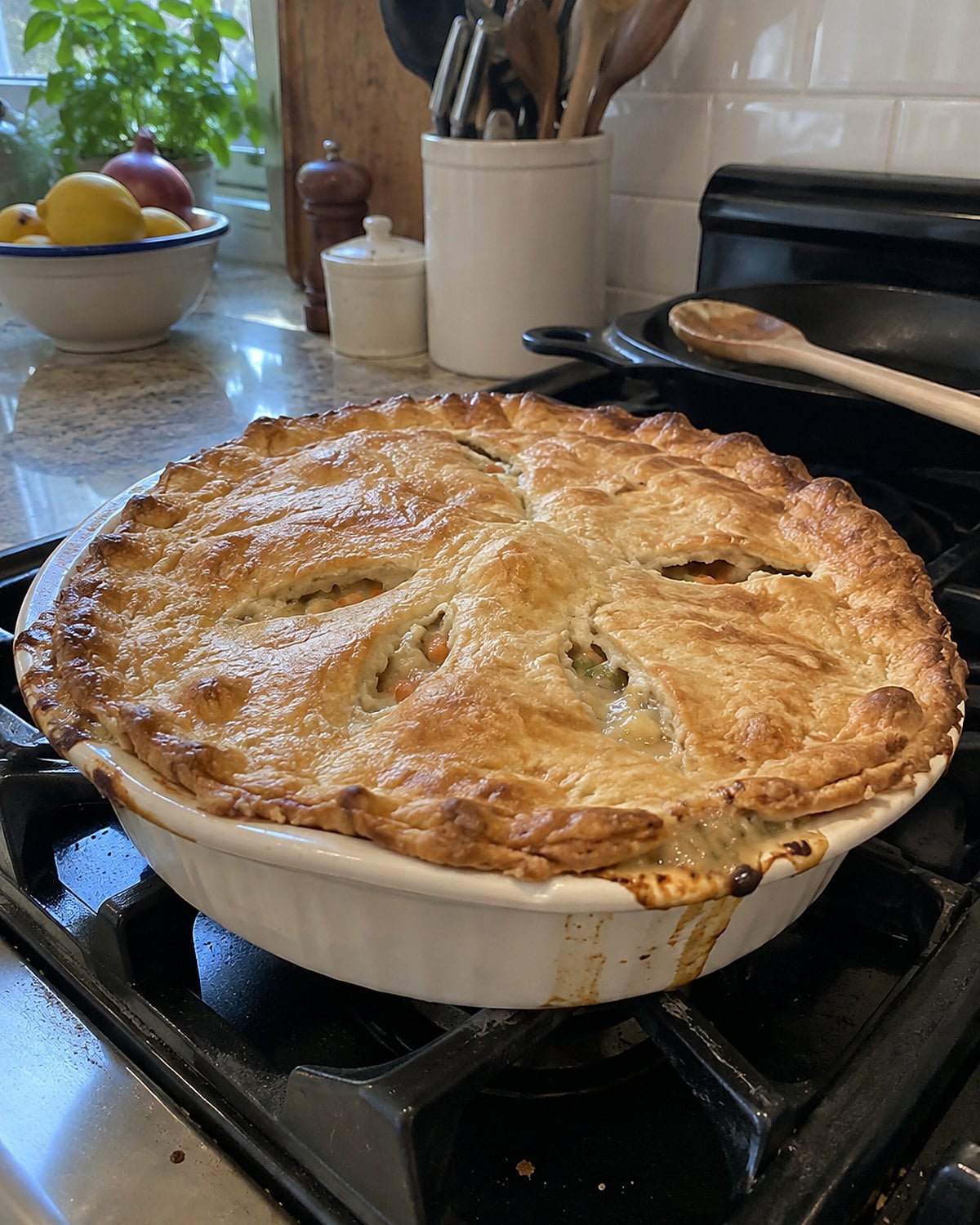 A chicken pot pie with a vented, uneven crust in a shallow baking dish on the stove.