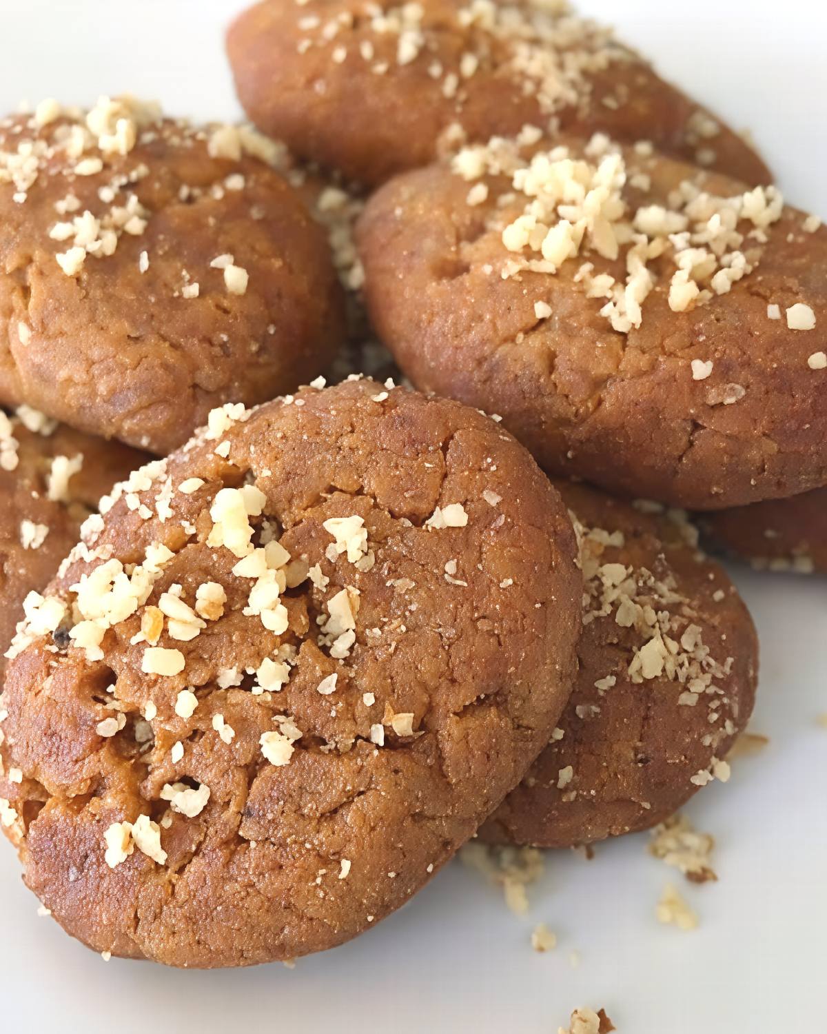 Soft, honey-soaked Greek Melomakarona cookies generously topped with finely crushed walnuts, served as a traditional European Christmas dessert.