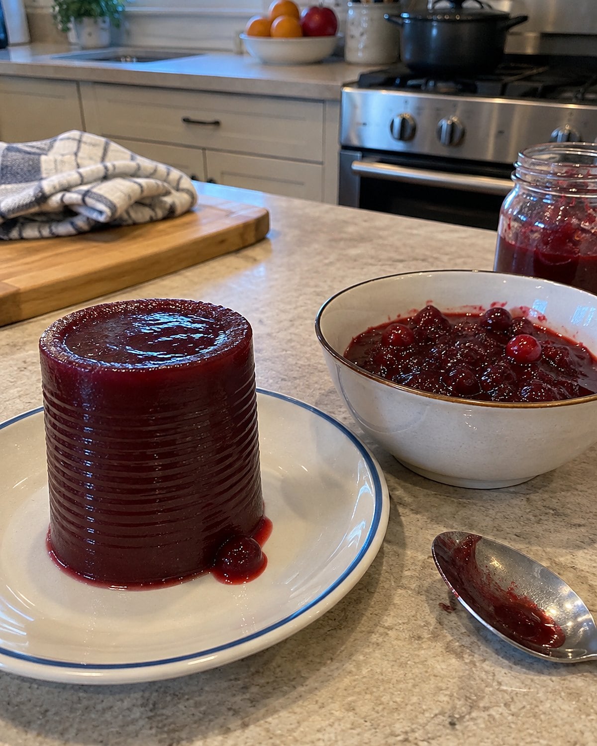 A ridged cylinder of cranberry sauce sits beside a bowl of whole-berry sauce on the counter.
