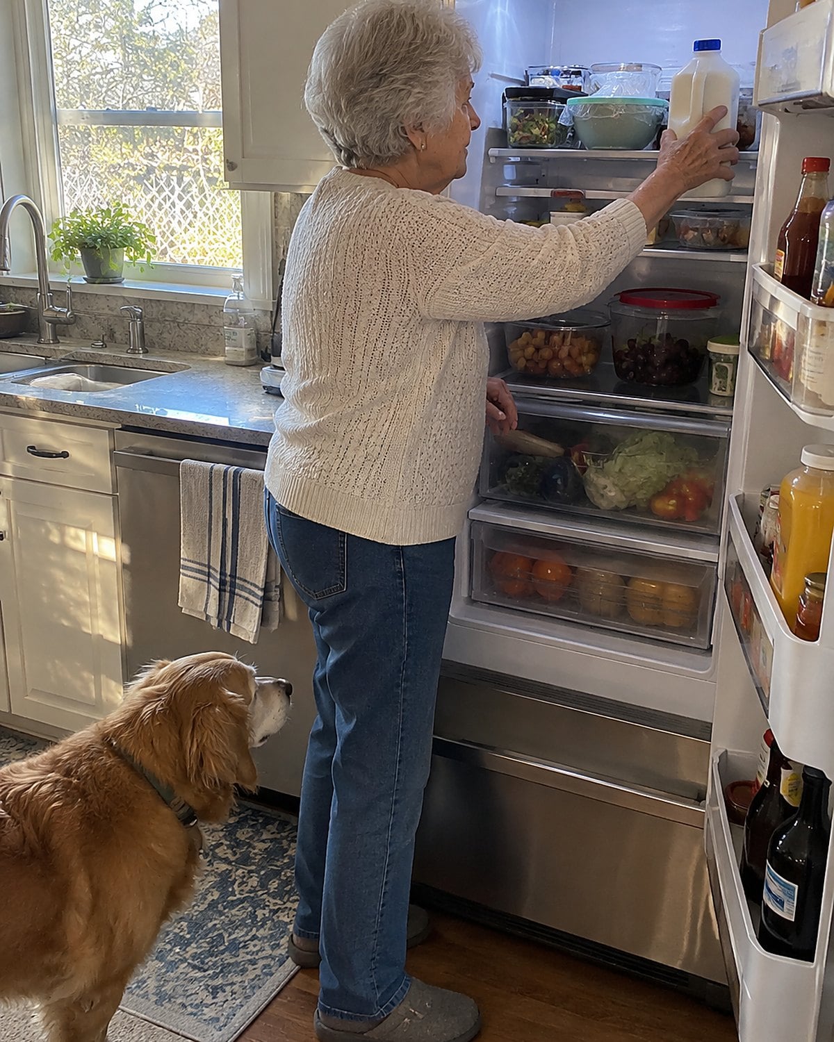 A hand moves a carton of milk from a refrigerator door rack toward a back shelf.