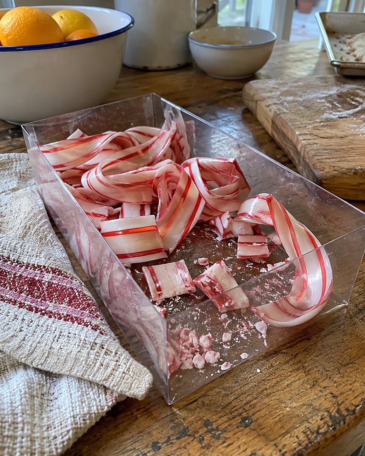 Broken striped ribbon candy lies inside an open cellophane box on a market stall.