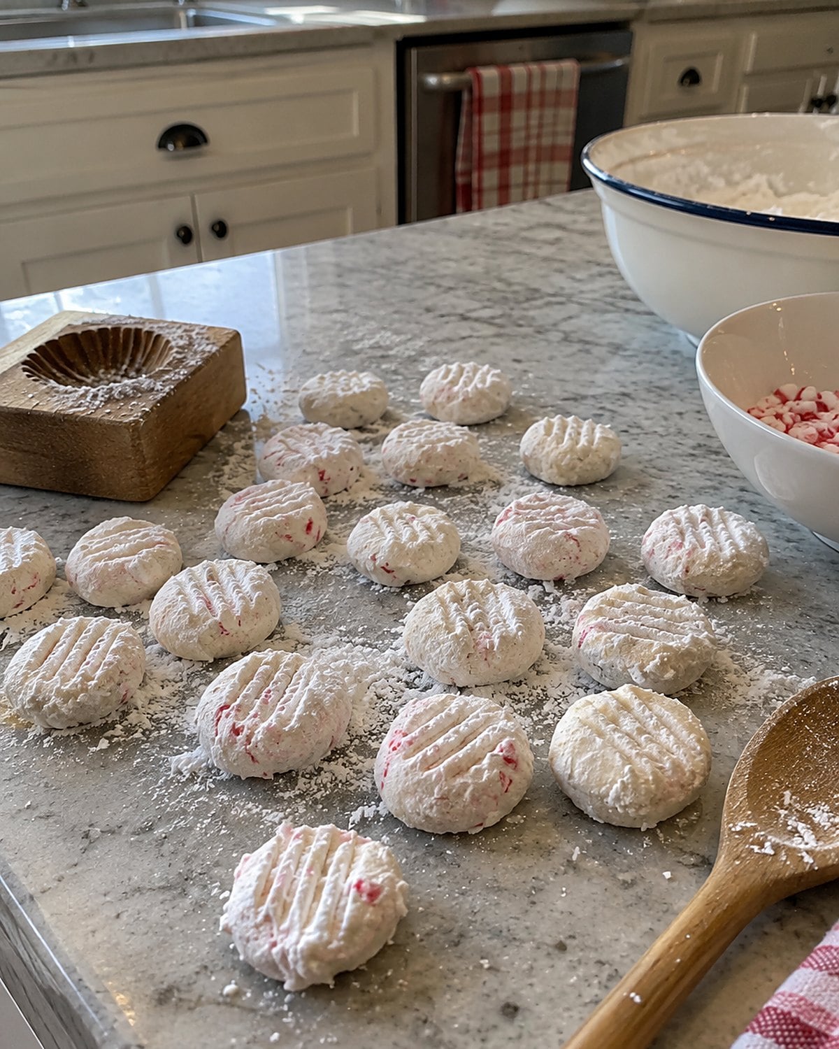 Fork-marked peppermint creams rest beside a small wooden mold on a kitchen counter.