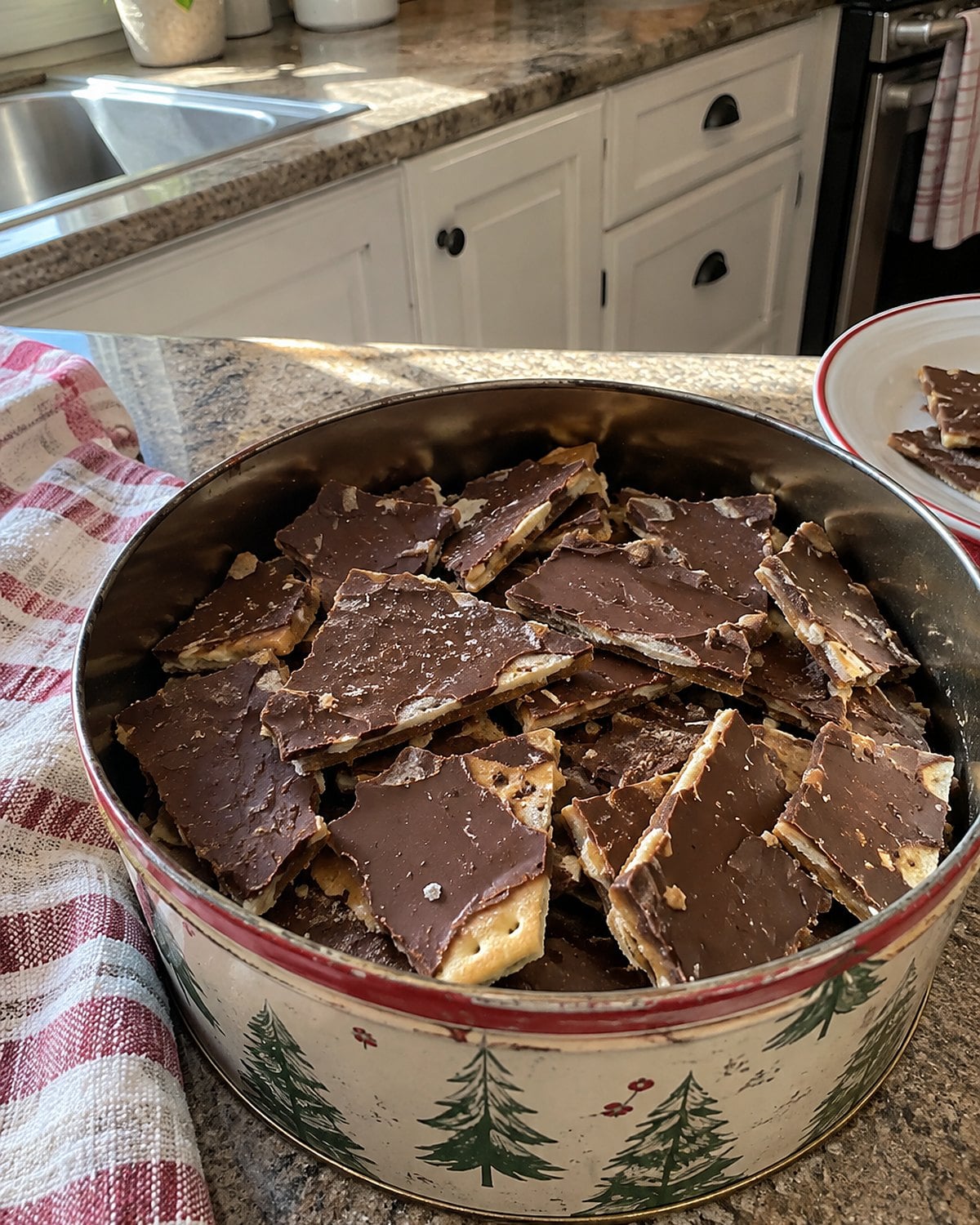 Broken saltine toffee fills an old cookie tin, with a cracker edge showing on one piece.