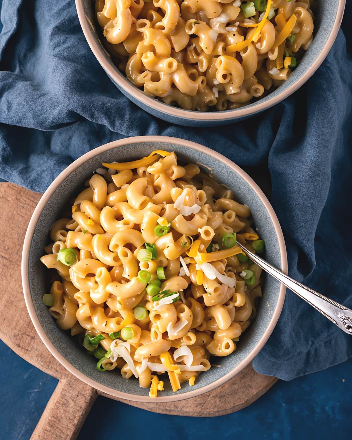 Bowls of rich and creamy Instant Pot mac and cheese with Boursin garnished with shredded cheese and green onions, perfect for Thanksgiving side dishes for a crowd.