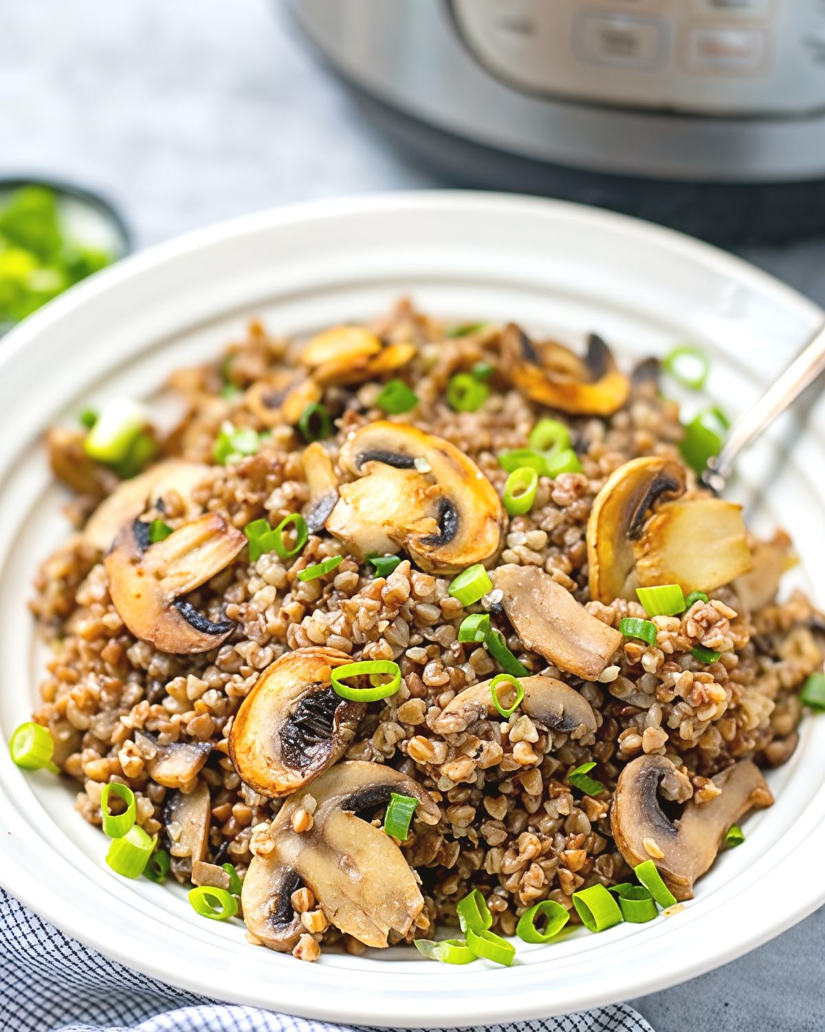 A bowl of fluffy Instant Pot buckwheat tossed with sautรฉed mushrooms and fresh green onions, served as one of the best gluten-free Thanksgiving side dishes.