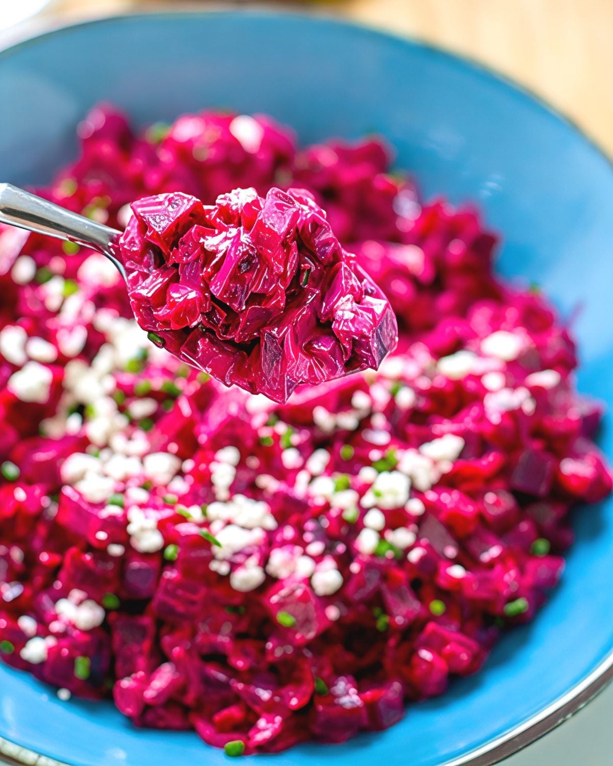 A spoonful of vibrant Instant Pot creamed beets topped with crumbled cheese and herbs, served in a blue bowl as one of the best gluten-free Thanksgiving side dishes.