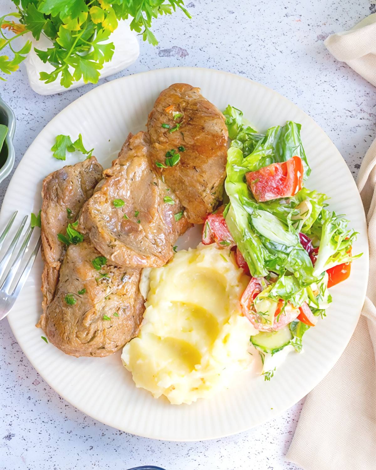 Juicy, boneless Instant Pot Pork Chops paired with smooth cauliflower mash and a side salad of lettuce, tomatoes, and cucumbers, featured as a delicious high protein low carb recipes dinner.