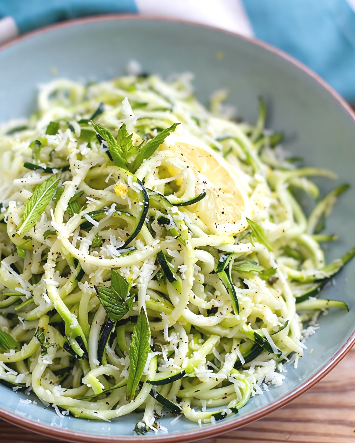 A bowl of fresh Instant Pot zucchini noodles tossed with garlic, lemon, fresh herbs, and shredded Parmesan cheese, perfect as easy Thanksgiving side dishes for a crowd.