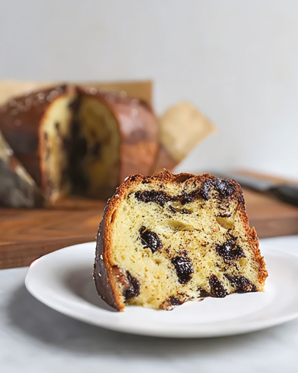 A slice of sweet Italian Panettone bread filled with rich chocolate swirls served on a white plate, featured as a classic European Christmas dessert.