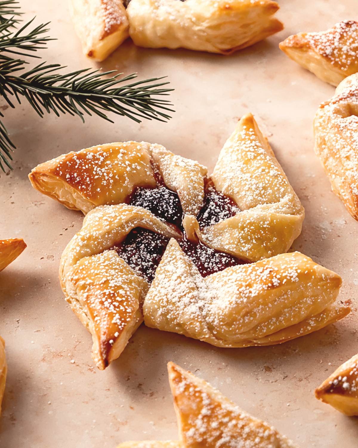 Traditional Finnish Joulutorttu pinwheel puff pastry filled with dark plum jam and dusted with powdered sugar, featured as a classic European Christmas dessert.