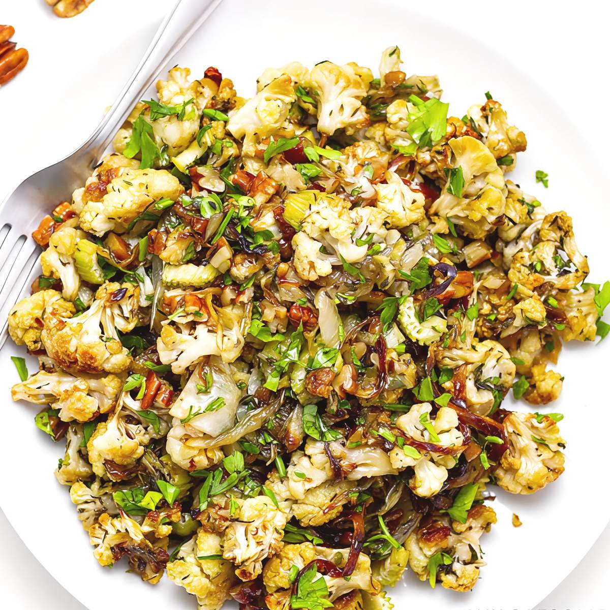 Low-carb keto Thanksgiving cauliflower stuffing side dish topped with fresh herbs and pecans