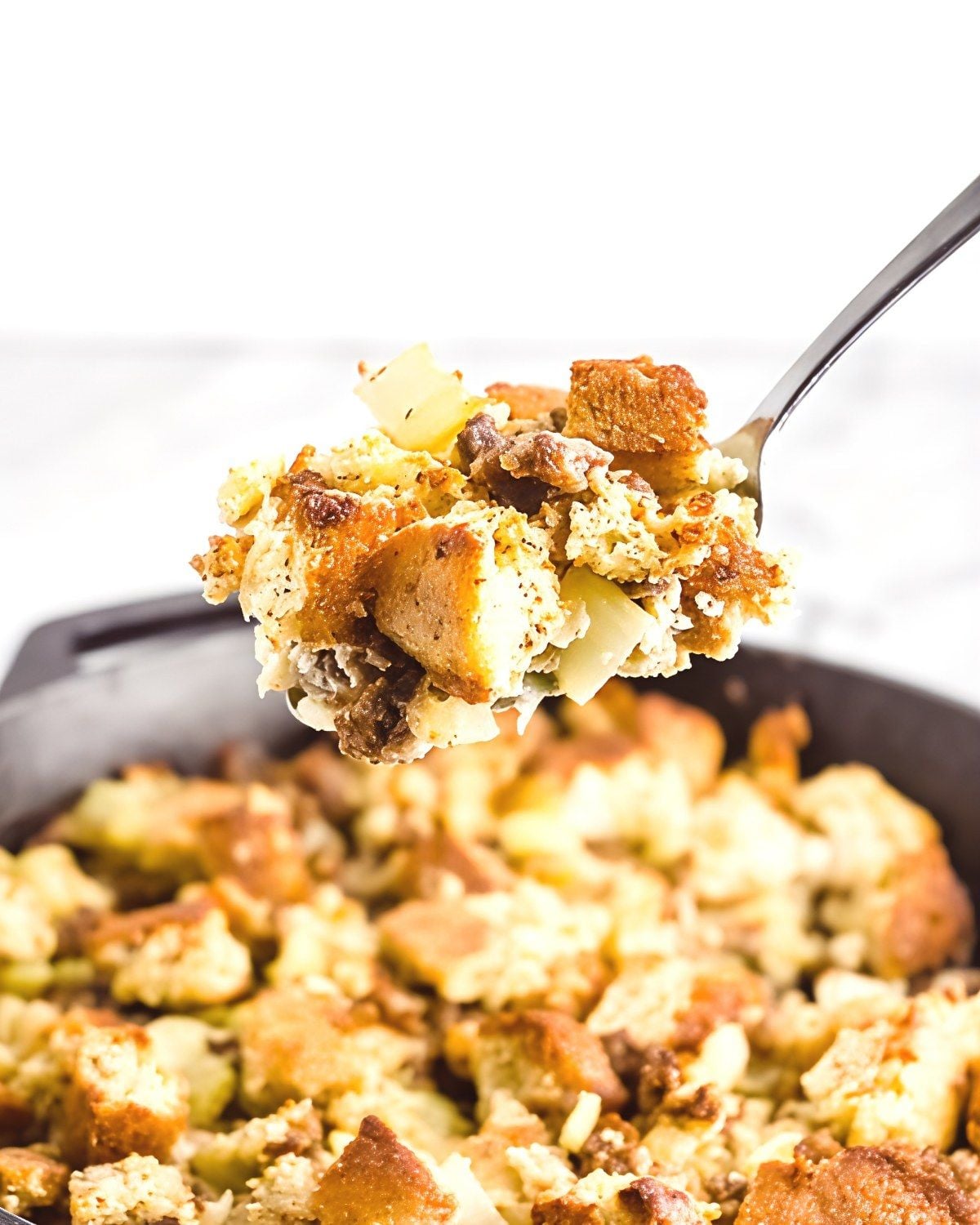 A close-up photograph of a savory Keto Cornbread Stuffing loaded with browned sausage, herbs, and low-carb vegetable for healthy keto thanksgiving sides.