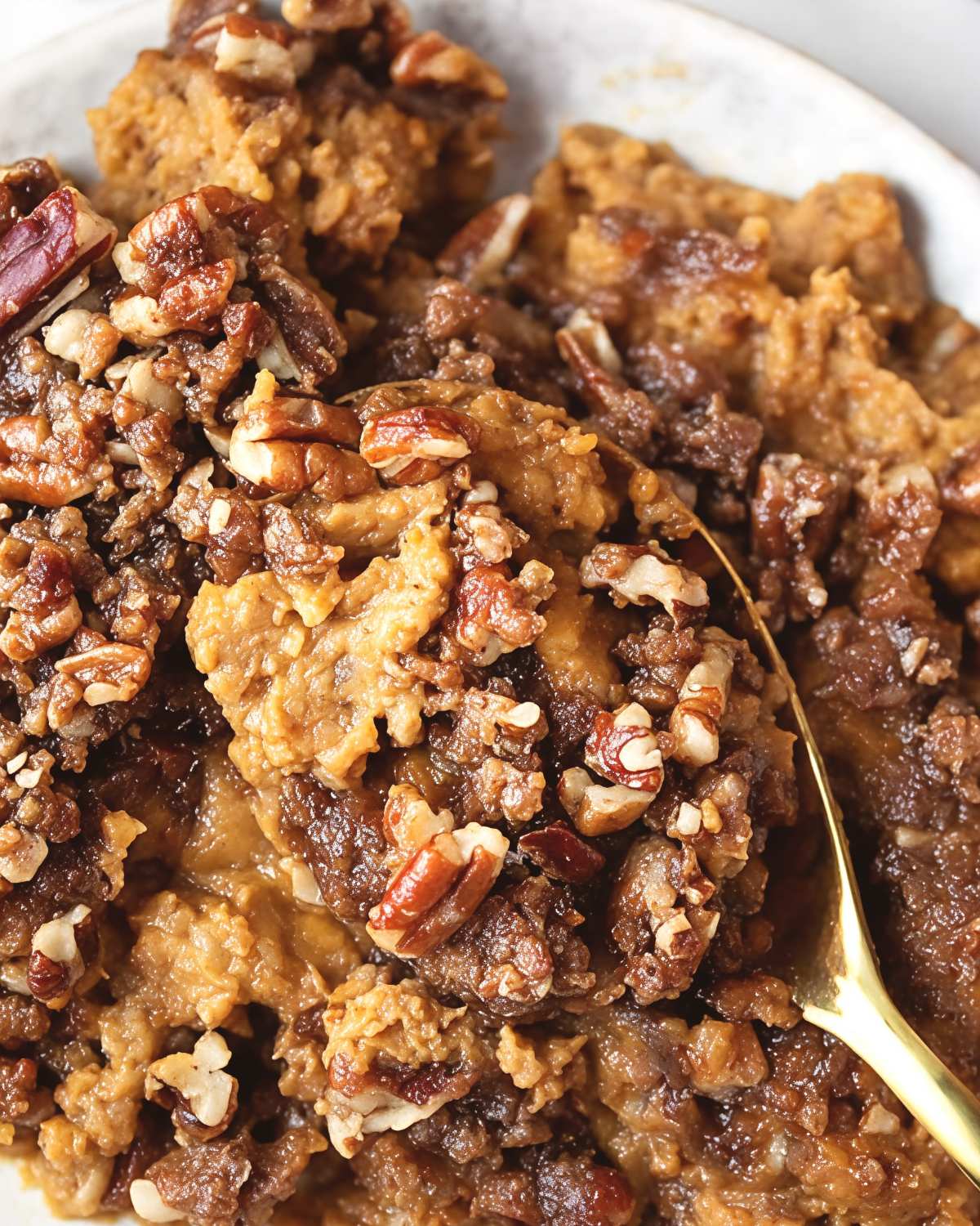 A gold spoon scoops into a warm keto sweet potato casserole topped with a crunchy pecan crumble, perfect for keto thanksgiving sides.