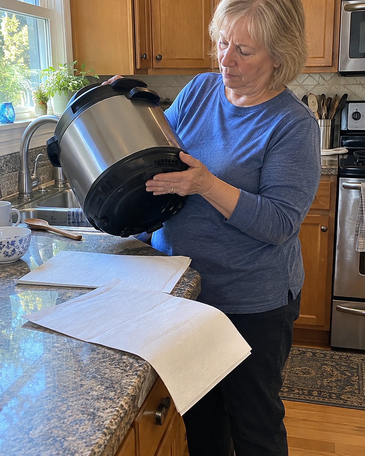 Appliance manuals spread beside an Instant Pot on a kitchen counter, with a hand checking the label underneath.