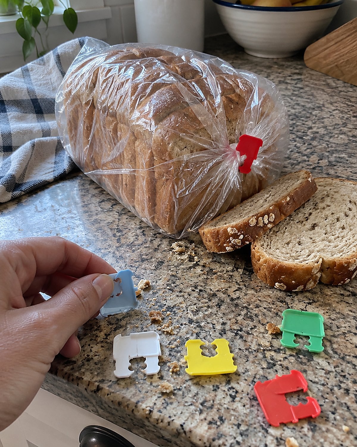 Plastic bread-bag clips scattered near a loaf on a kitchen counter.