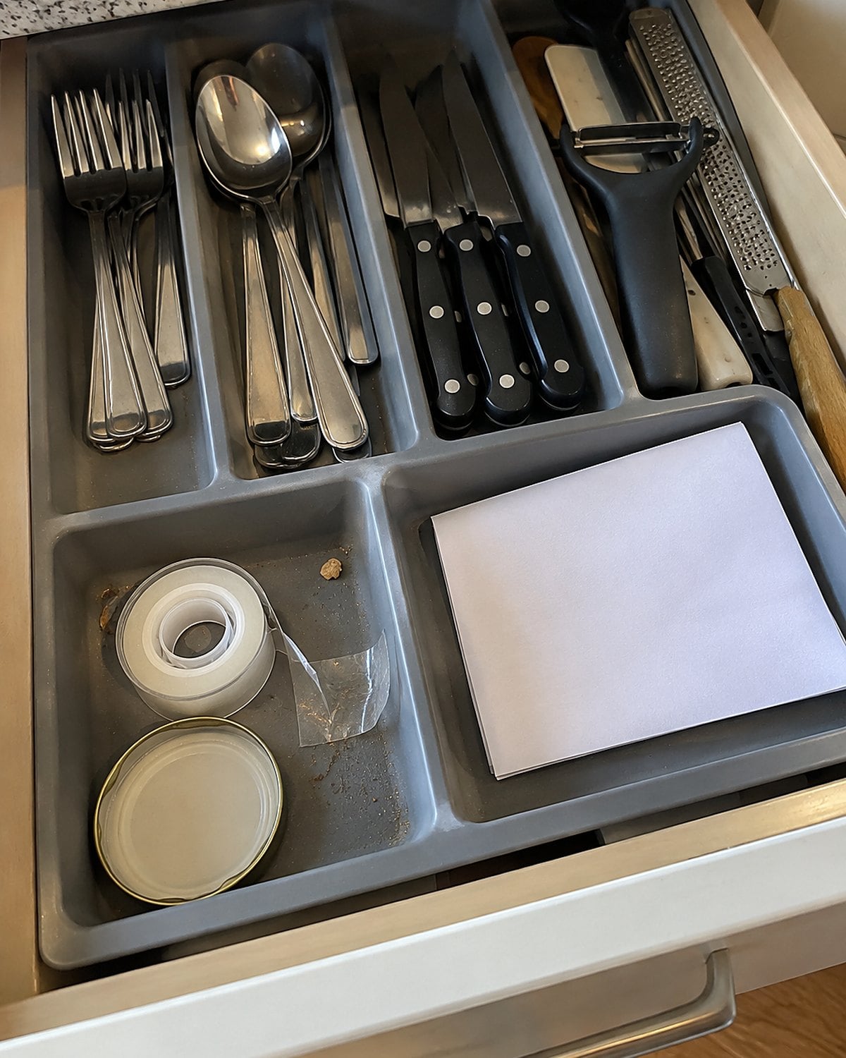 A small roll of tape in a drawer tray beside a folded note.