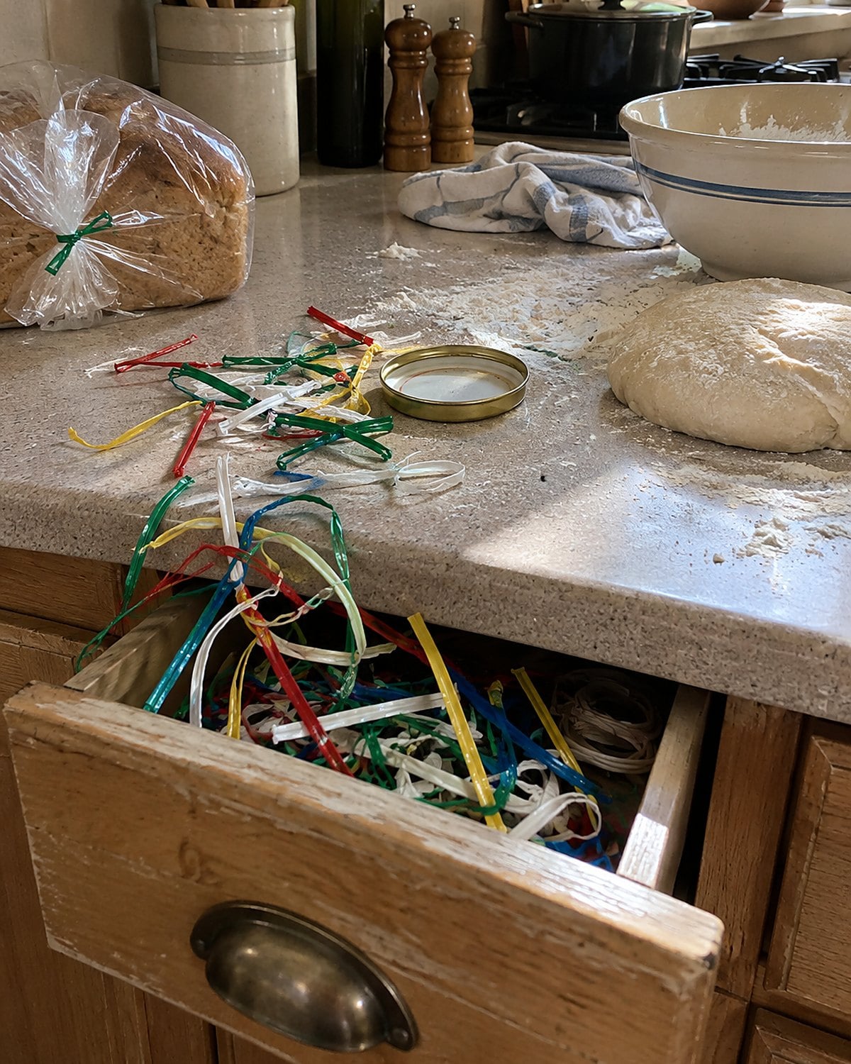 A tangle of bread-bag twist ties spilling from an open drawer onto a flour-dusted counter.