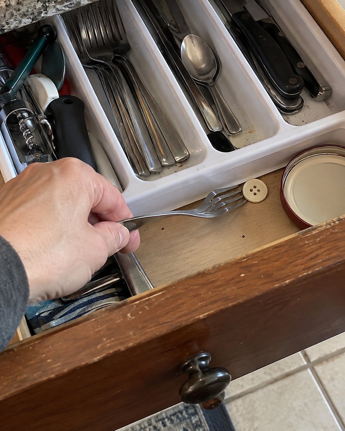 A bent takeout fork caught under the edge of a plastic drawer organizer.