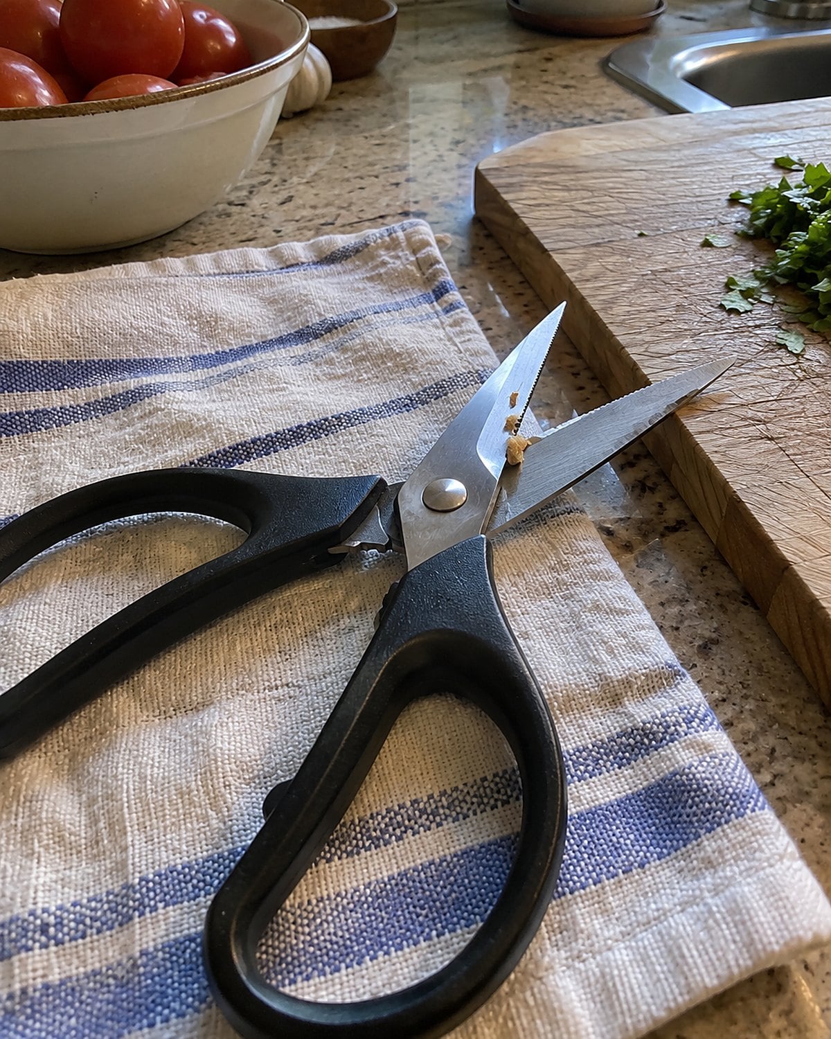 Clean kitchen shears resting open on a towel beside a cutting board.