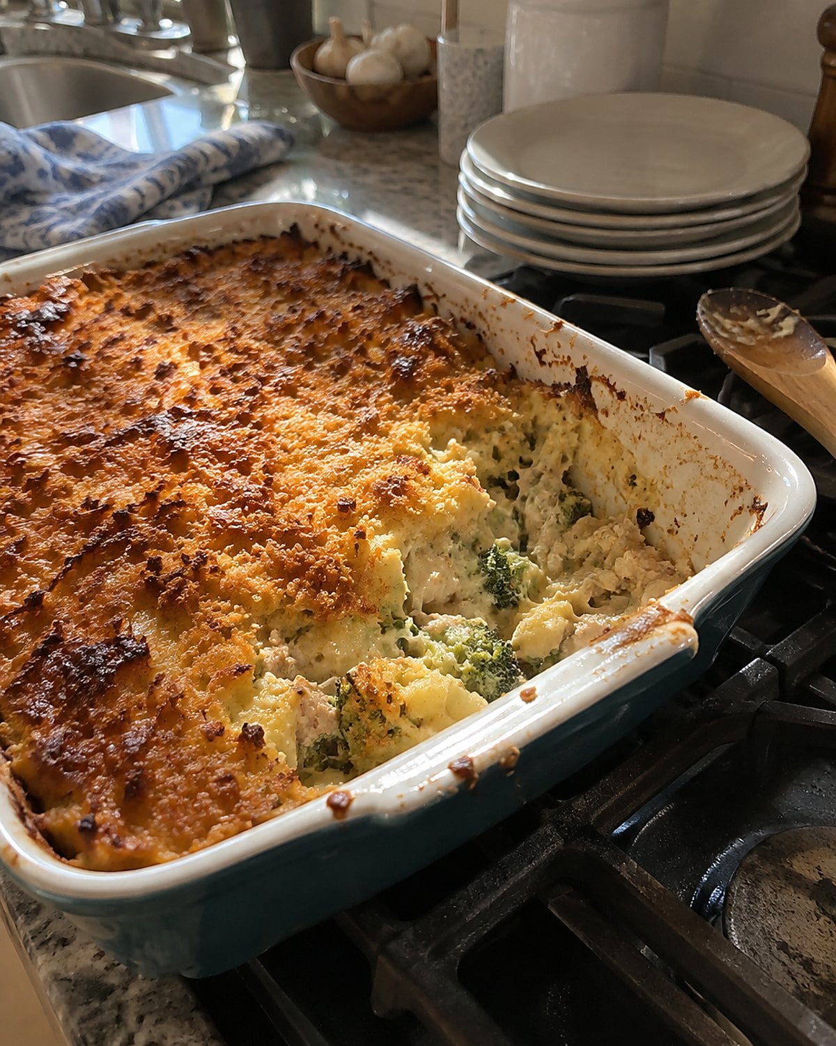 A baking dish of casserole sits on the stove, its browned top parted to show the center.