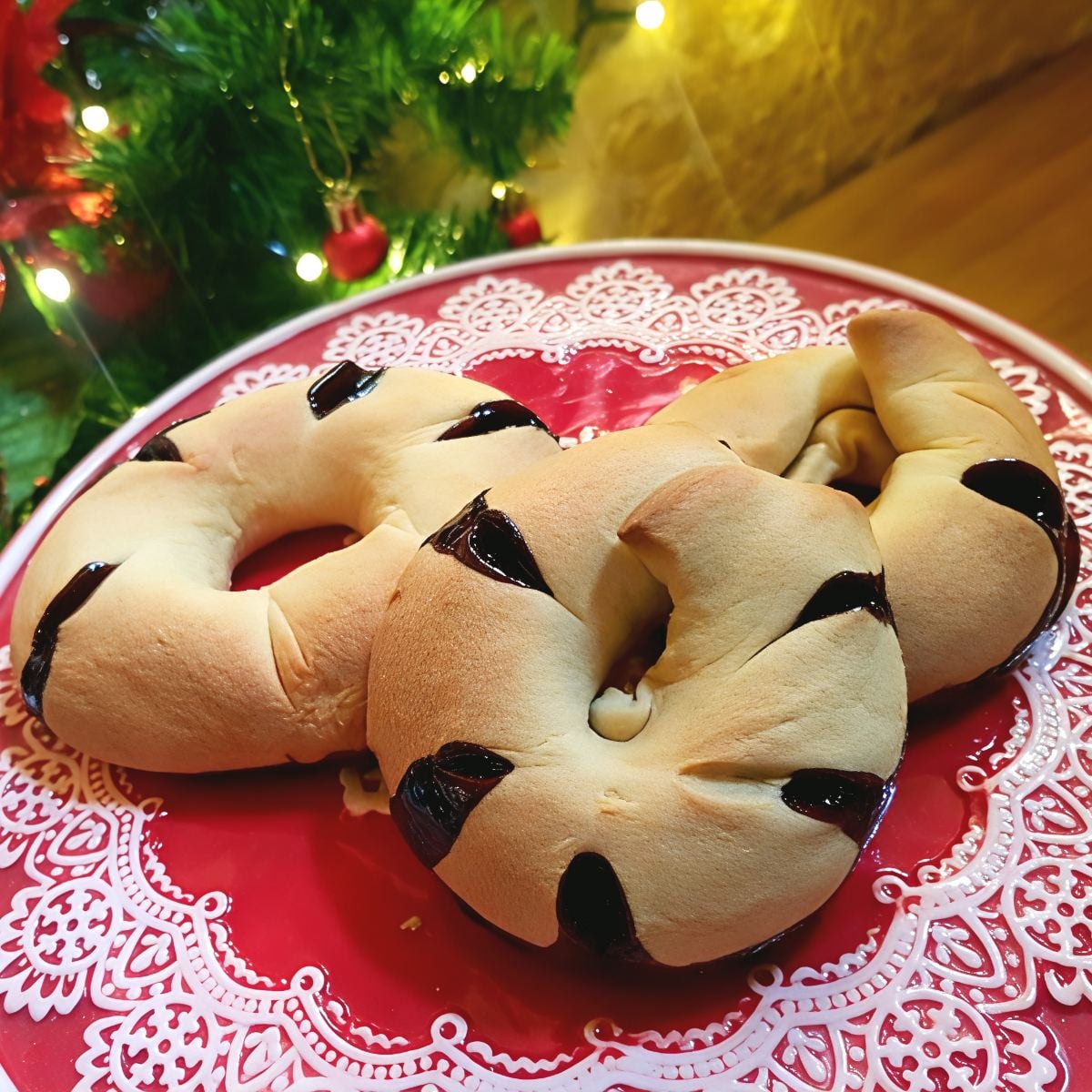 Traditional Maltese Qagħaq tal-Għasel honey rings filled with spiced treacle peek through slashed pastry crusts on a festive plate, featured as a unique European Christmas dessert.