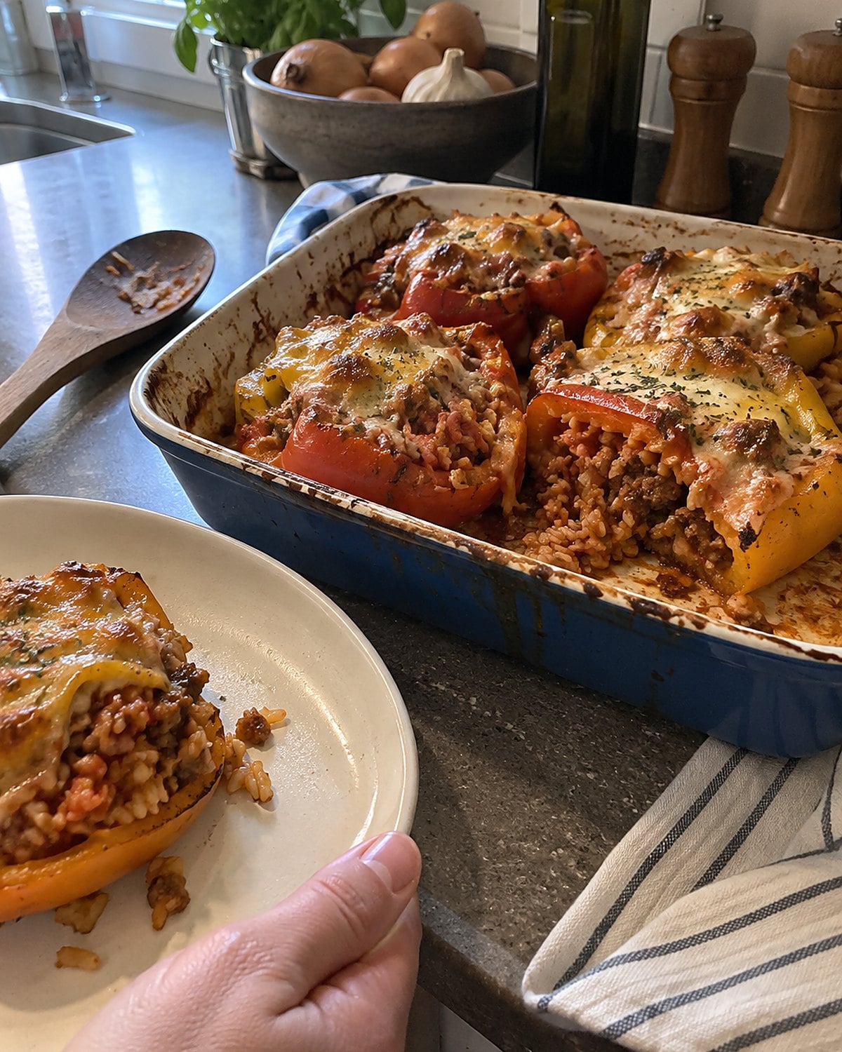 Stuffed pepper halves in a baking dish, with one cut open to show tender rice.