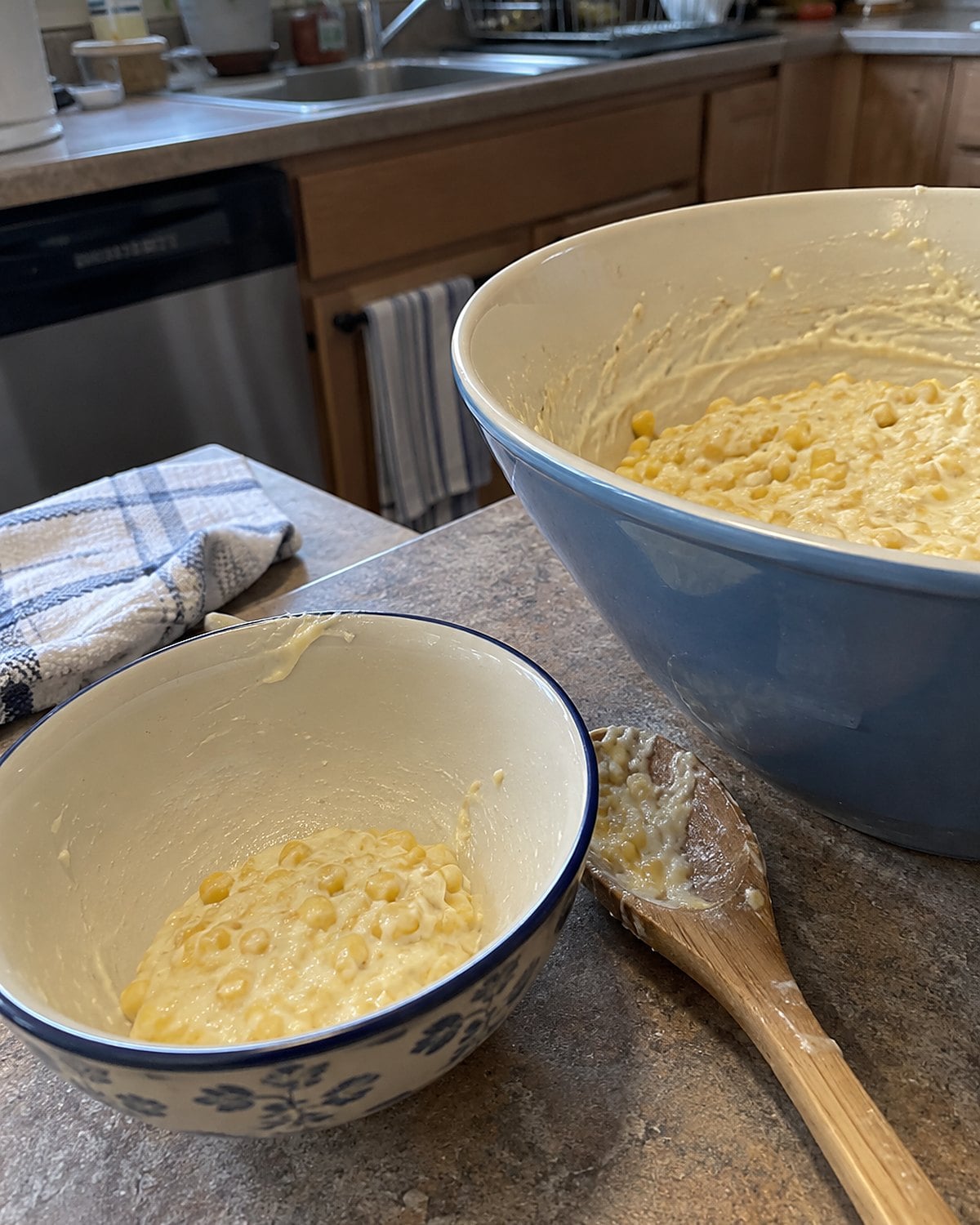 A small bowl holding the last spoonful of creamed corn sits beside a mixing bowl on the counter.