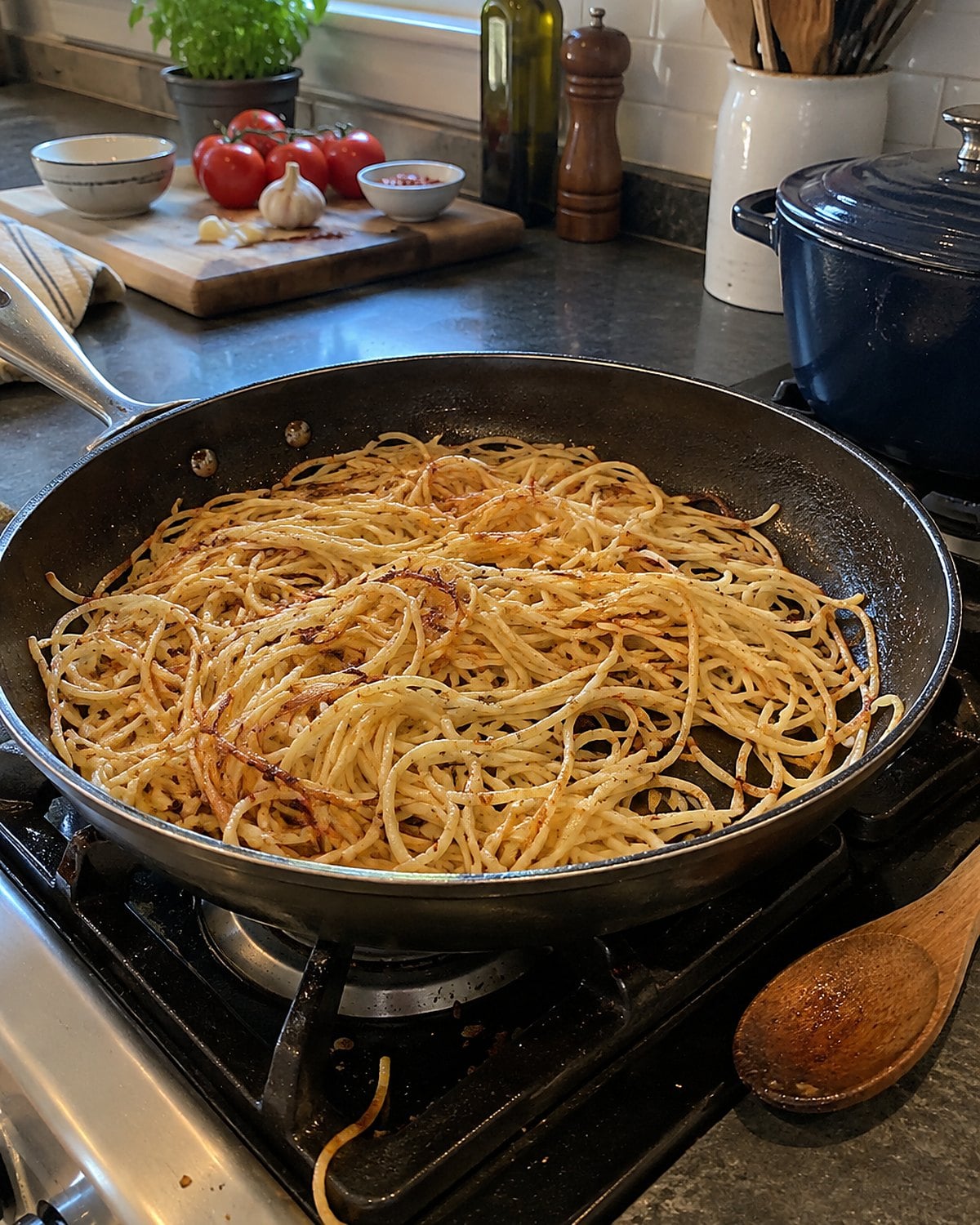Cold spaghetti sizzles in a wide skillet, with browned strands caught at the edge.