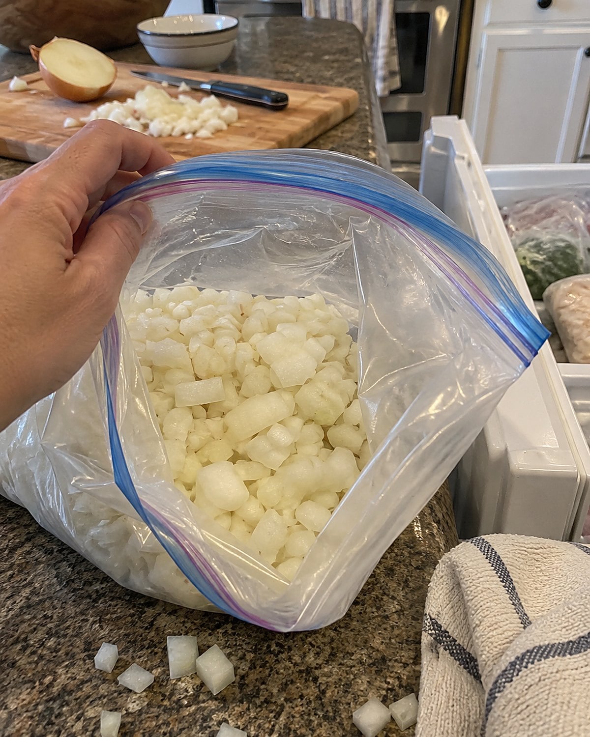 Chopped onion bits fill a partly open freezer bag beside a freezer drawer.