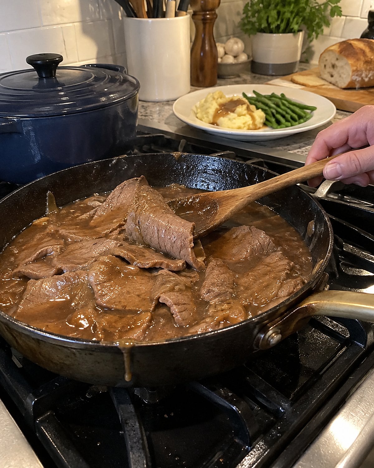 Thin roast beef slices warm in brown gravy in a small skillet on the stove.