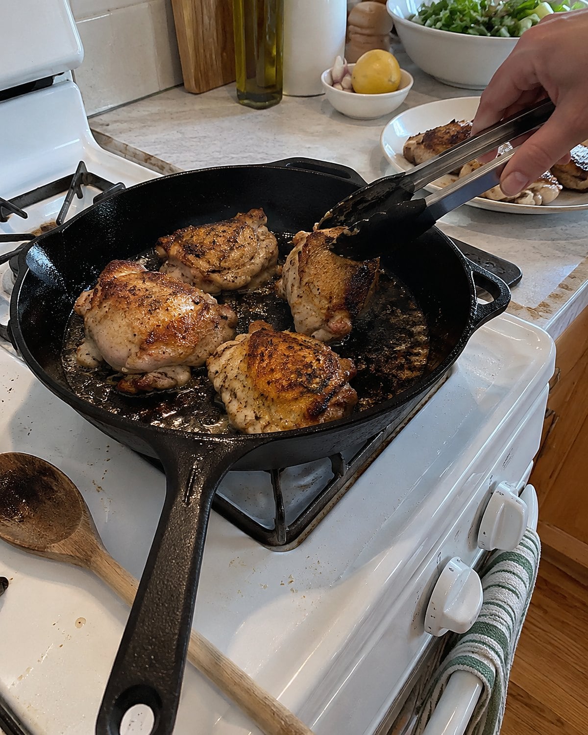 Pieces of chicken skin crisp in a skillet on a white stove, with a few browned edges.