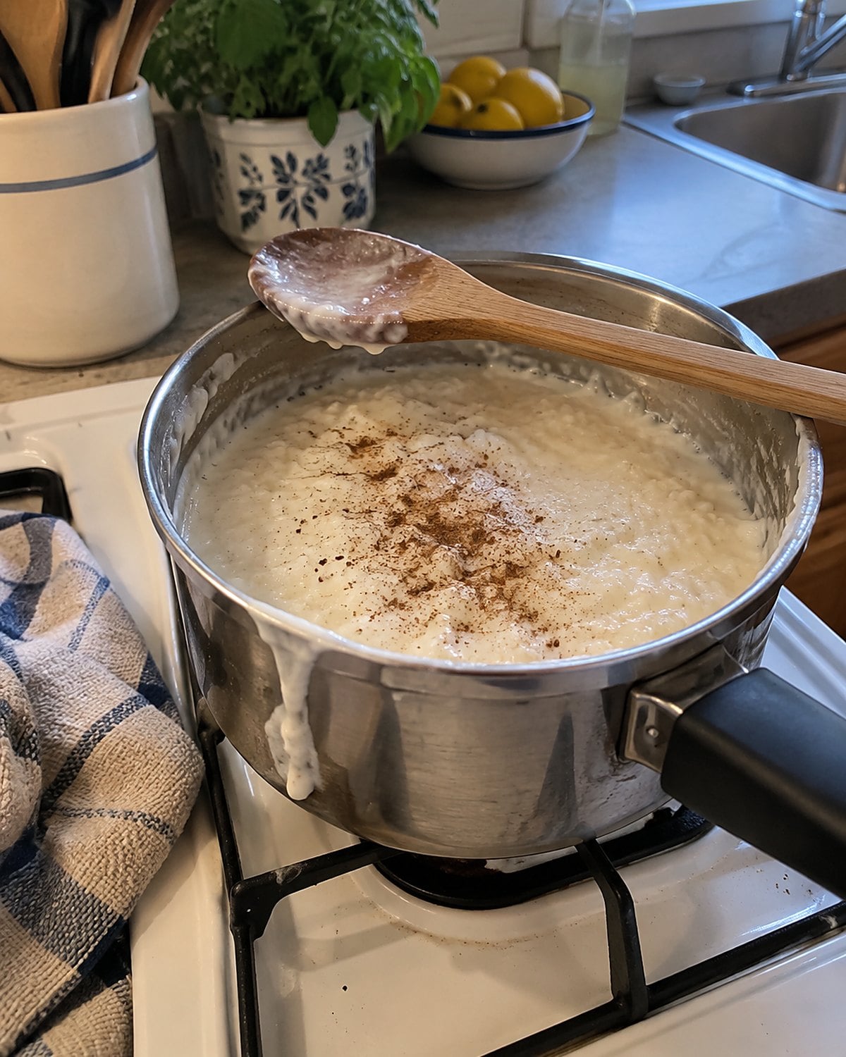 A small pot of rice pudding on a white stove, with a wooden spoon resting across its rim.
