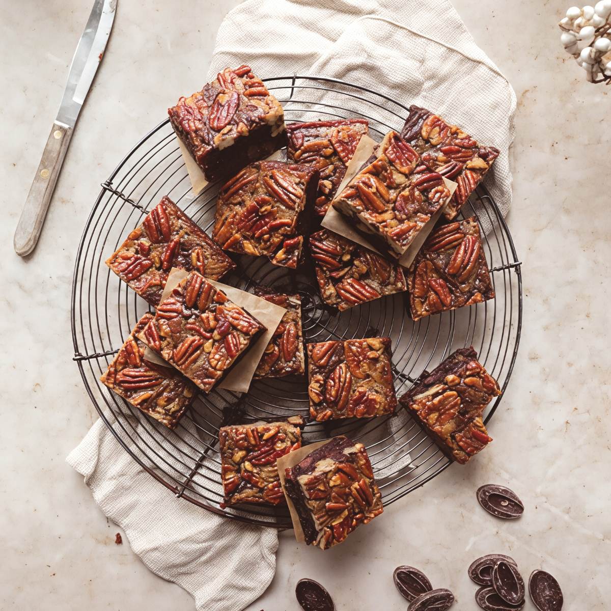 Rich chocolate pecan pie brownies topped with whole caramelized pecans on a wire cooling rack for Thanksgiving finger food ideas.