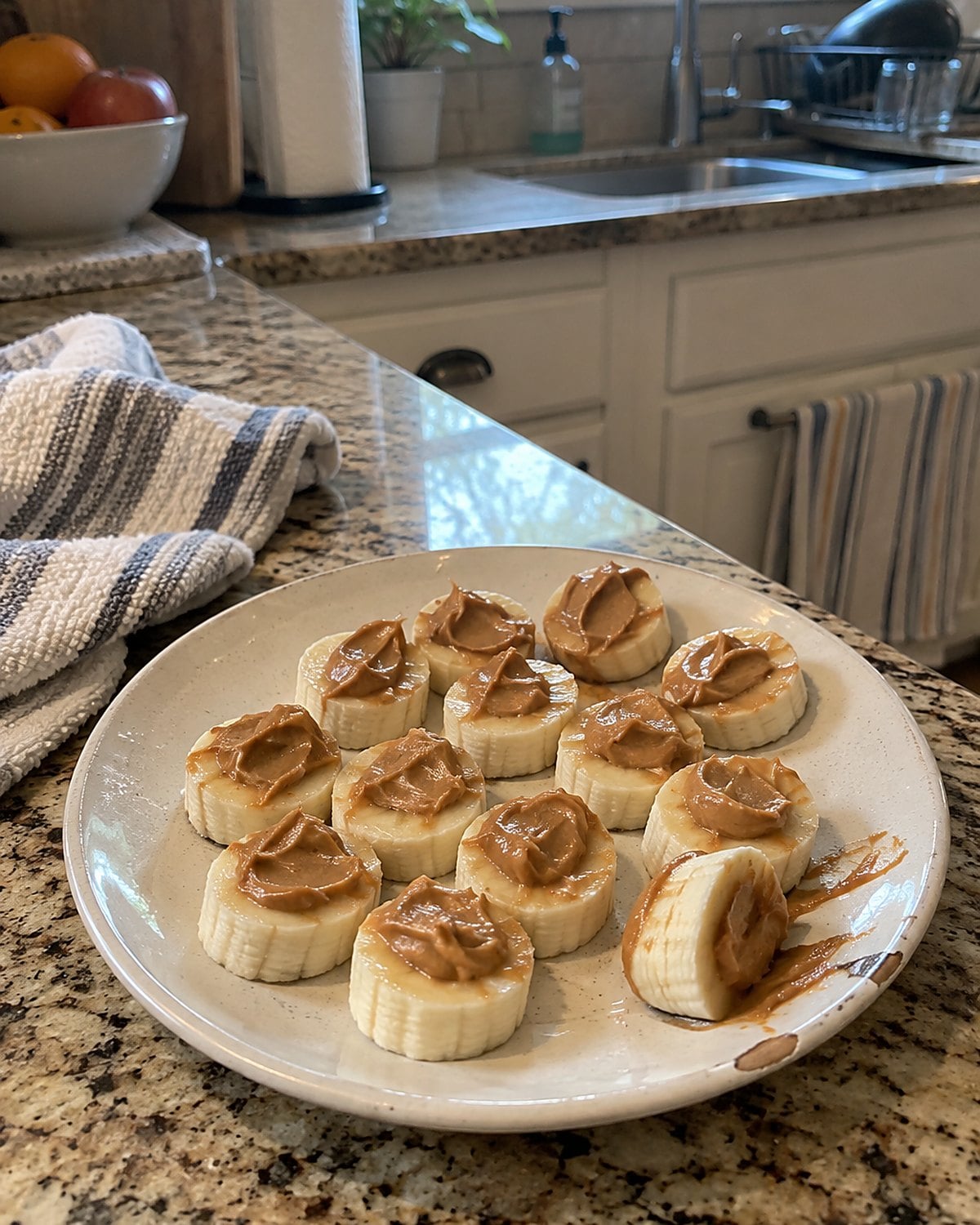 Banana rounds topped with peanut butter on a small kitchen plate.